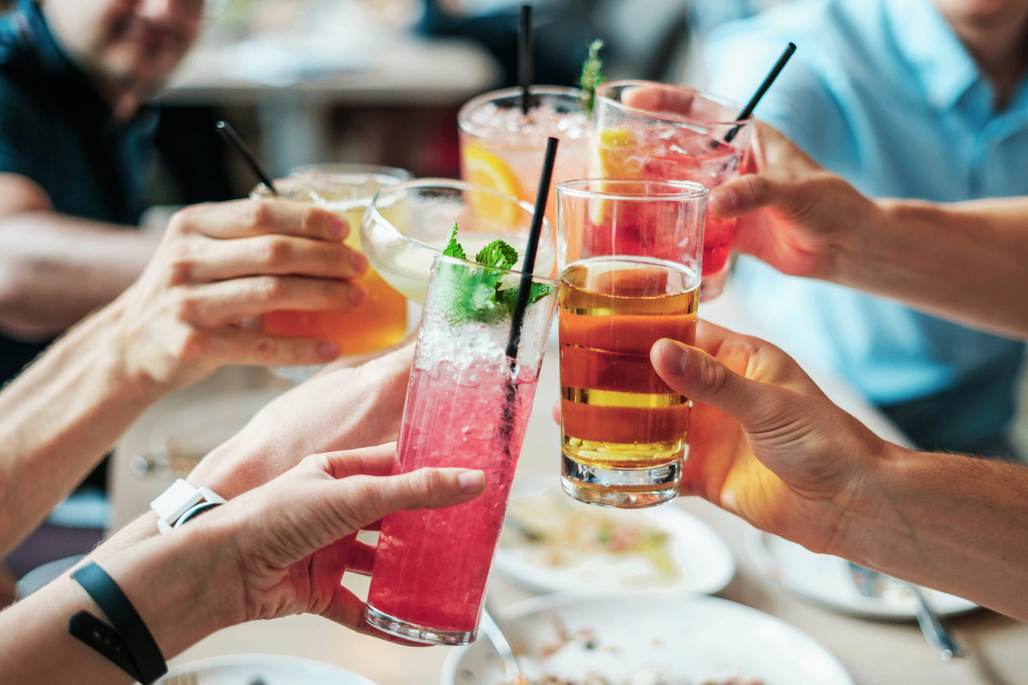 Friends toasting with colorful drinks at a restaurant